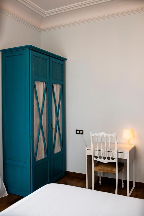 A small room with a blue wardrobe, a white desk, a matching chair, and a lit table lamp—evoking the cozy ambiance often found in boutique hotels in Cantabria. The light-colored walls and wooden floor complete the inviting setting.