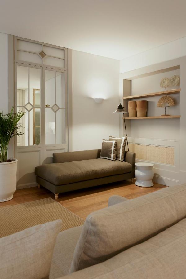 Top 12 Boutique Hotels in Porto, Portugal 27 Stylish living room reminiscent of boutique hotels in Porto, featuring a modern brown chaise lounge, neutral-toned sofa, an indoor plant in a white pot, built-in shelves with decorative items, and soft lighting that creates a cozy atmosphere.