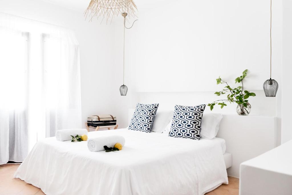 7 Best Hotels in the Aeolian Islands 8 A bright, minimalist bedroom—like those in the best hotels in the Aeolian Islands—features a white bed with patterned black-and-white pillows, rolled towels with lemons, a green plant on the nightstand, pendant lights, and sunlight streaming through sheer curtains.