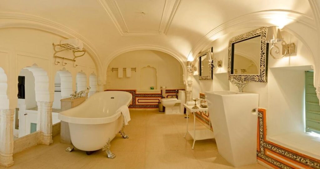 Authentic Heritage Hotels in Mandawa 2 A luxurious, spacious bathroom in the style of the finest hotels in Mandawa, with a clawfoot bathtub, ornate mirrors, arched alcoves, and decorative wall details. Warm golden lighting enhances its elegant, classical design.