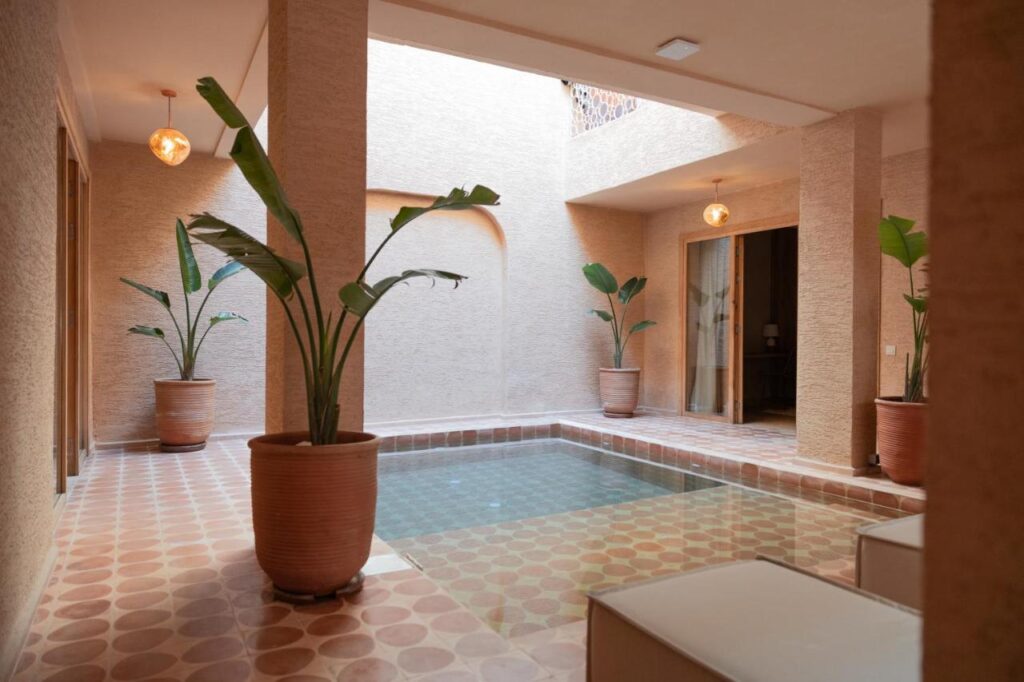 10 Unique Riads in Marrakech with Pool 24 Experience the serene charm of riads in Marrakech with pool, featuring an inviting indoor pool surrounded by lush plants in pots.