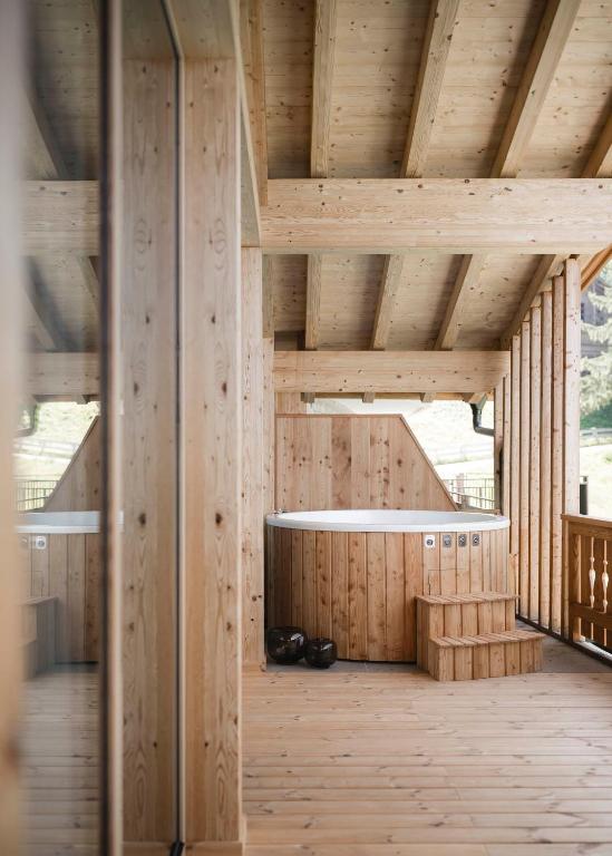 Wooden deck with a round hot tub, small steps, and kettlebells, surrounded by wood beams—natural light streaming in, evoking the cozy charm found at the best hotels in the Dolomites.