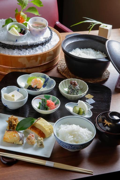15 Unique Hotels in Tokyo: Coolest hotels 45 A traditional Japanese meal set with rice, assorted small dishes including fish, tofu, pickles, soup, and sashimi—much like the artful presentations found at unique hotels in Tokyo—elegantly arranged on a tray with chopsticks and a pot of steamed rice.