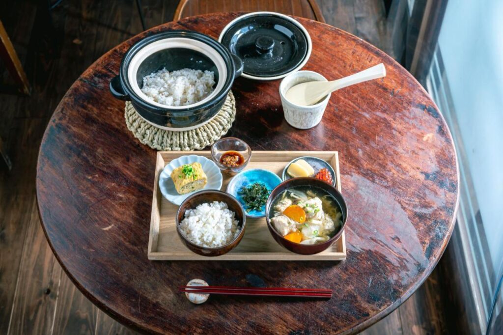 15 Unique Hotels in Tokyo: Coolest hotels 21 A wooden table set with a traditional Japanese meal, including rice, miso soup, side dishes, and chopsticks—an experience reminiscent of dining at unique hotels in Tokyo.