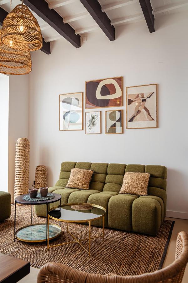 Unique Boutique Hotels in Menorca 31 A modern living room with an olive green tufted sofa, textured cushions, two round coffee tables, and woven decor accents—evoking the relaxed elegance found in boutique hotels in Menorca. Natural light fills the space.