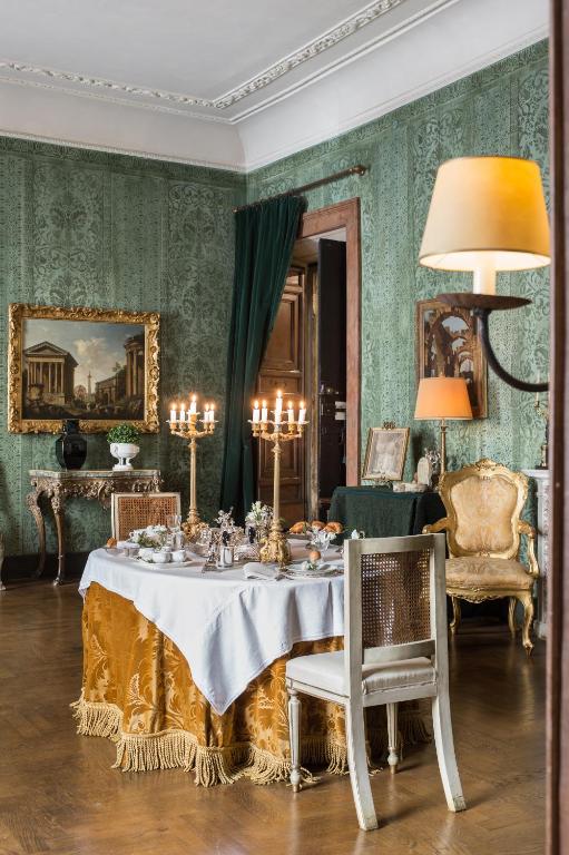 3 Days in Rome Itinerary 3 Elegant dining room with vintage decor, like those found in boutique hotels in Rome, featuring a table set for a meal with white and gold cloths, a candelabra, ornate chairs, green wallpaper, framed artwork, and classical furnishings. Warm, inviting lighting.