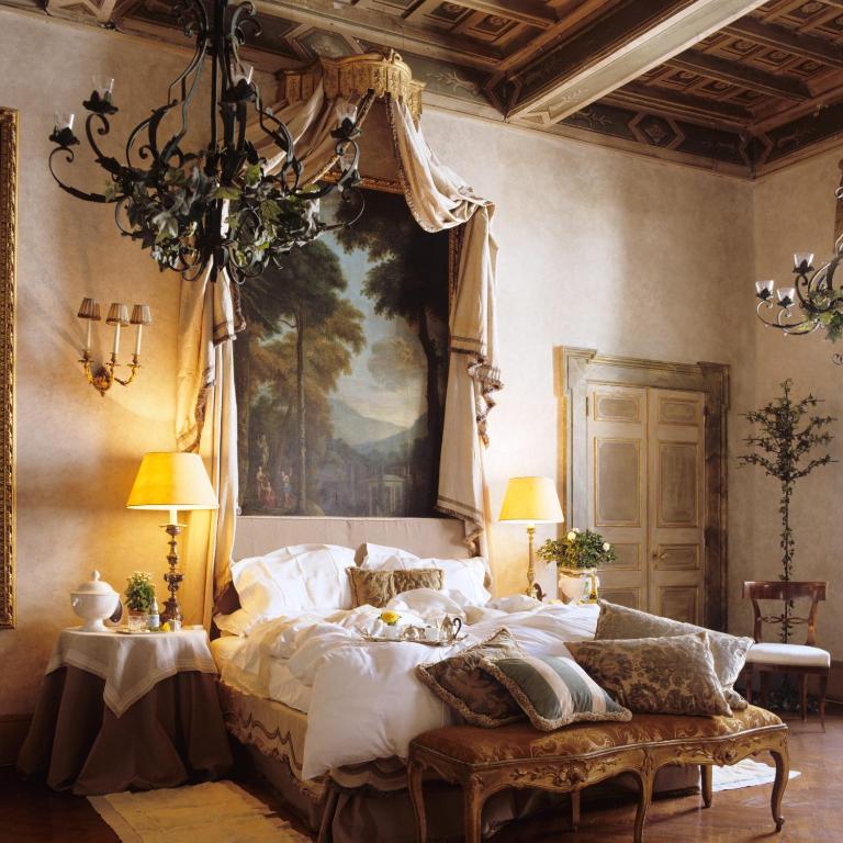3 Days in Rome Itinerary 2 Elegant bedroom with ornate chandeliers, a richly decorated ceiling, and a large wall mural behind the bed—evoking the luxurious, old-world atmosphere found in boutique hotels in Rome.
