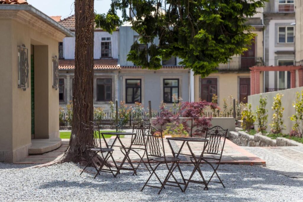 Top 12 Boutique Hotels in Porto, Portugal 15 A group of chairs and a tree in a courtyard evoke the charming outdoor spaces often found at boutique hotels in Porto.