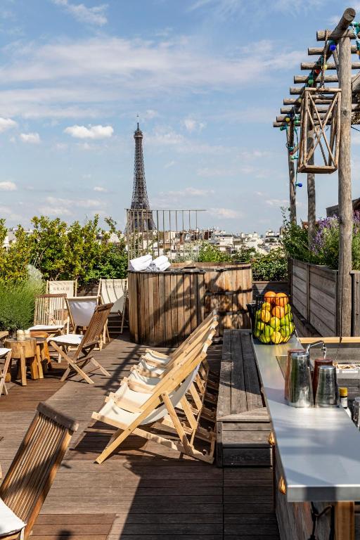 13 Unique Hotels in Paris for a Stylish Stay 45 Rooftop terrace with wooden lounge chairs and greenery, offering a clear view of the Eiffel Tower—an inviting spot found at one of the unique hotels in Paris under a blue sky with scattered clouds.