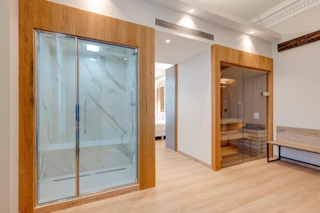 13 Unique Hotels in Barcelona, Spain 37 Modern room with light wood floors, a glass-enclosed shower with marble walls on the left, and a sauna on the right. Minimalist decor and integrated lighting offer a tranquil retreat typical of unique hotels in Barcelona.