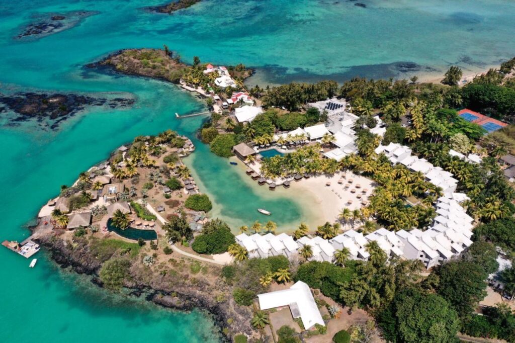 Most Unique Adults Only Hotels in Mauritius, Indian Ocean 2 Aerial view of a tropical resort with white buildings, lush greenery, a pool, sun loungers on the beach, and turquoise water—perfect for those seeking adults only hotels in Mauritius surrounded by clear blue sea and islands.