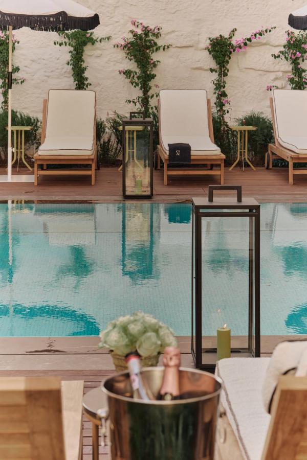 Top 12 Boutique Hotels in Porto, Portugal 5 Poolside scene at one of the boutique hotels in Porto, with lounge chairs, umbrellas, potted plants, and flowering vines along a white wall. In the foreground, a table holds a silver ice bucket with champagne and a bouquet of white flowers.