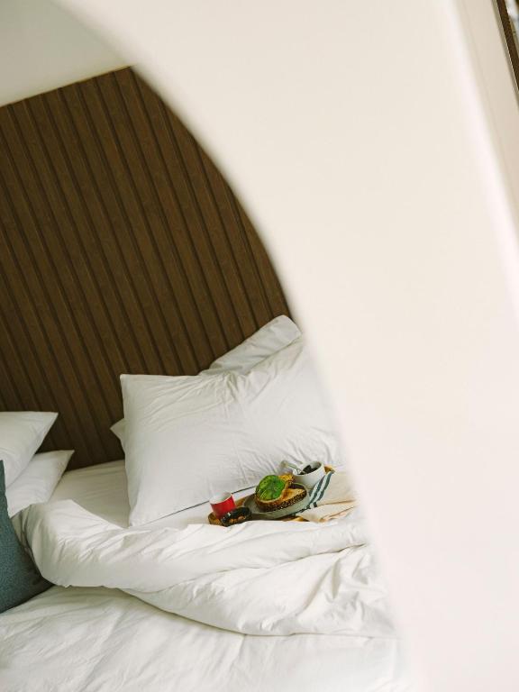 9 Unique Boutique Hotels in Lima 23 A tray with a drink and a small meal sits on a neatly made bed with white pillows and sheets, partially viewed through a white archway—capturing the cozy elegance of boutique hotels in Lima.