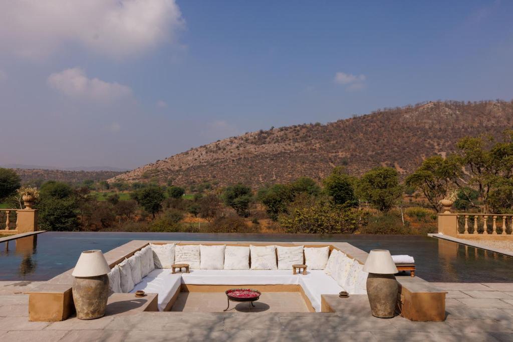 12 BEST Boutique Hotels in Jaipur 30 A sunken outdoor seating area with white cushions and a central table, surrounded by water, overlooks a scenic landscape—evoking the tranquil charm found at boutique hotels in Jaipur.