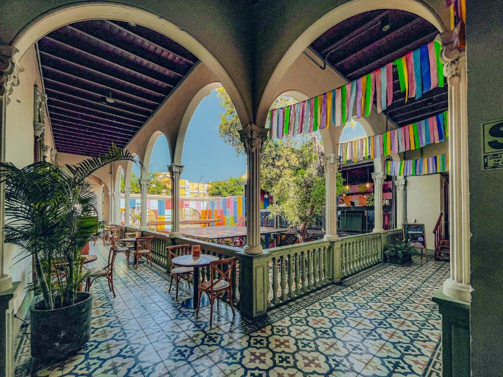 9 Unique Boutique Hotels in Lima 37 A colorful courtyard inspired by boutique hotels in Lima features patterned tile floors, arched columns, wooden furniture, leafy plants, and vibrant streamers overhead. Sunlight pours through open arches, creating a festive atmosphere.