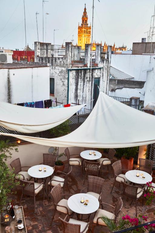 Rooftop terrace with round tables and wicker chairs under white canopies, overlooking old buildings and the Giralda tower in Seville, Spain—an inviting setting often found at boutique hotels in Seville.